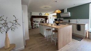 Eine moderne Küche mit Kochinsel, Pendelleuchten und einem rustikalen Backofen aus Ziegeln.