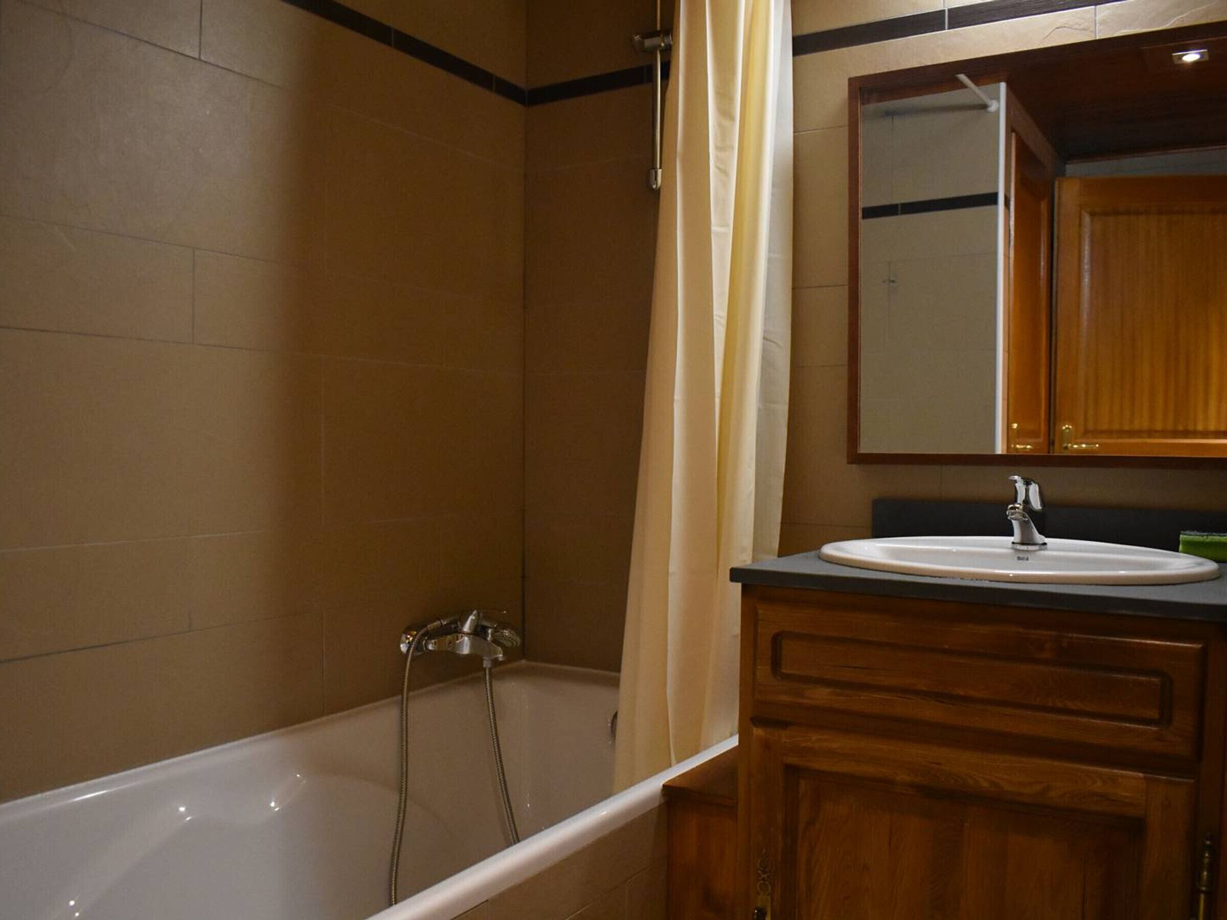 Une salle de bain avec une baignoire, un lavabo et un meuble-lavabo en bois.