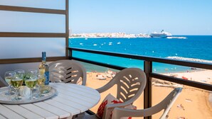 A balcony with a table set for dining, overlooking a beach with a cruise ship in the distance. - Modern Seaside Apartment, Sant Antoni (San Antonio de Calonge)