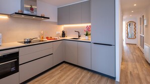 A modern kitchen with grey cabinets, a black countertop, and a wooden floor. - Modern Seaside Apartment, Sant Antoni (San Antonio de Calonge)