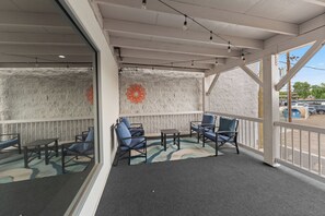 A covered outdoor seating area with chairs and tables, a decorative wall, and a view of the street. - Downtown Yuma · River Walk · Bikes · Monthly (Yuma)