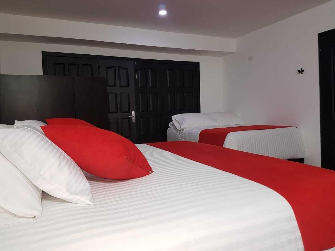 A hotel room with two beds, each with white and red bedding.
