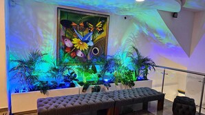 Un vestíbulo con un gran mural de mariposas y flores, un banco y plantas en macetas.