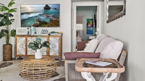 A living room with a sofa, a coffee table, a television, and a cabinet. - Dolphin Bay Bungalow – Waterfront Pool, Kayaks, & Walk to Indian Rocks Beach (Indian Rocks Beach)
