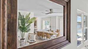 A dining area with a white table, wicker chairs, and a ceiling fan. - Dolphin Bay Bungalow – Waterfront Pool, Kayaks, & Walk to Indian Rocks Beach (Indian Rocks Beach)