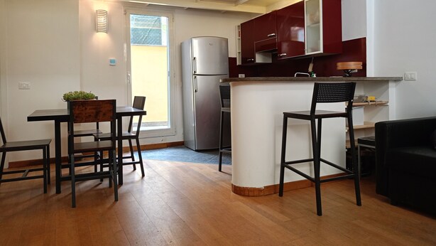 A modern kitchen with a built-in refrigerator, wooden dining table, and bar stools. - Delightful Loft in Pigneto - to Colosseum in 10 minutes (Roma)