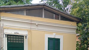 A building with a green door and window shutters, a tiled patio, and outdoor furniture. - Delightful Loft in Pigneto - to Colosseum in 10 minutes (Roma)