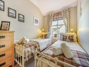 A bedroom with two beds, a dresser, and a window with curtains. - 1 bedroom accommodation in Keswick (Keswick)