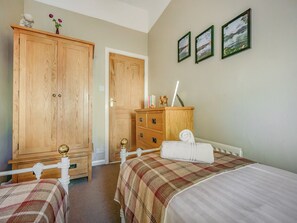 A bedroom with two beds, a wooden wardrobe, and a dresser with a mirror. - 1 bedroom accommodation in Keswick (Keswick)