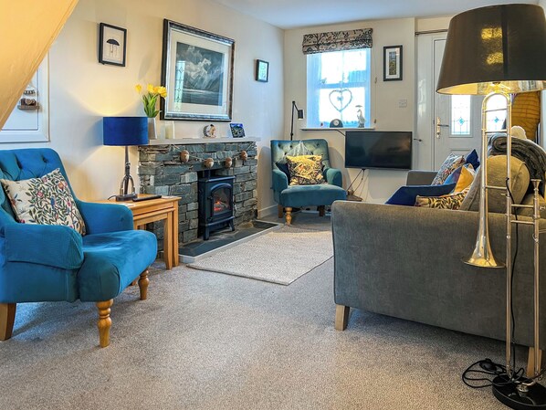 A cozy living room with a fireplace, blue and grey sofas, a TV, and a lamp.