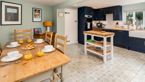 A modern kitchen with dark cabinets, a wooden dining table, and a small island with a bowl.