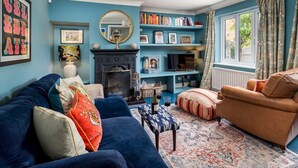 A cozy living room with a blue sofa, a brown armchair, and a patterned rug.