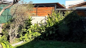 A modern house with a sloped roof, surrounded by a well-maintained garden with various plants and a lawn. - Fast Track SCL AirPort (Santiago)