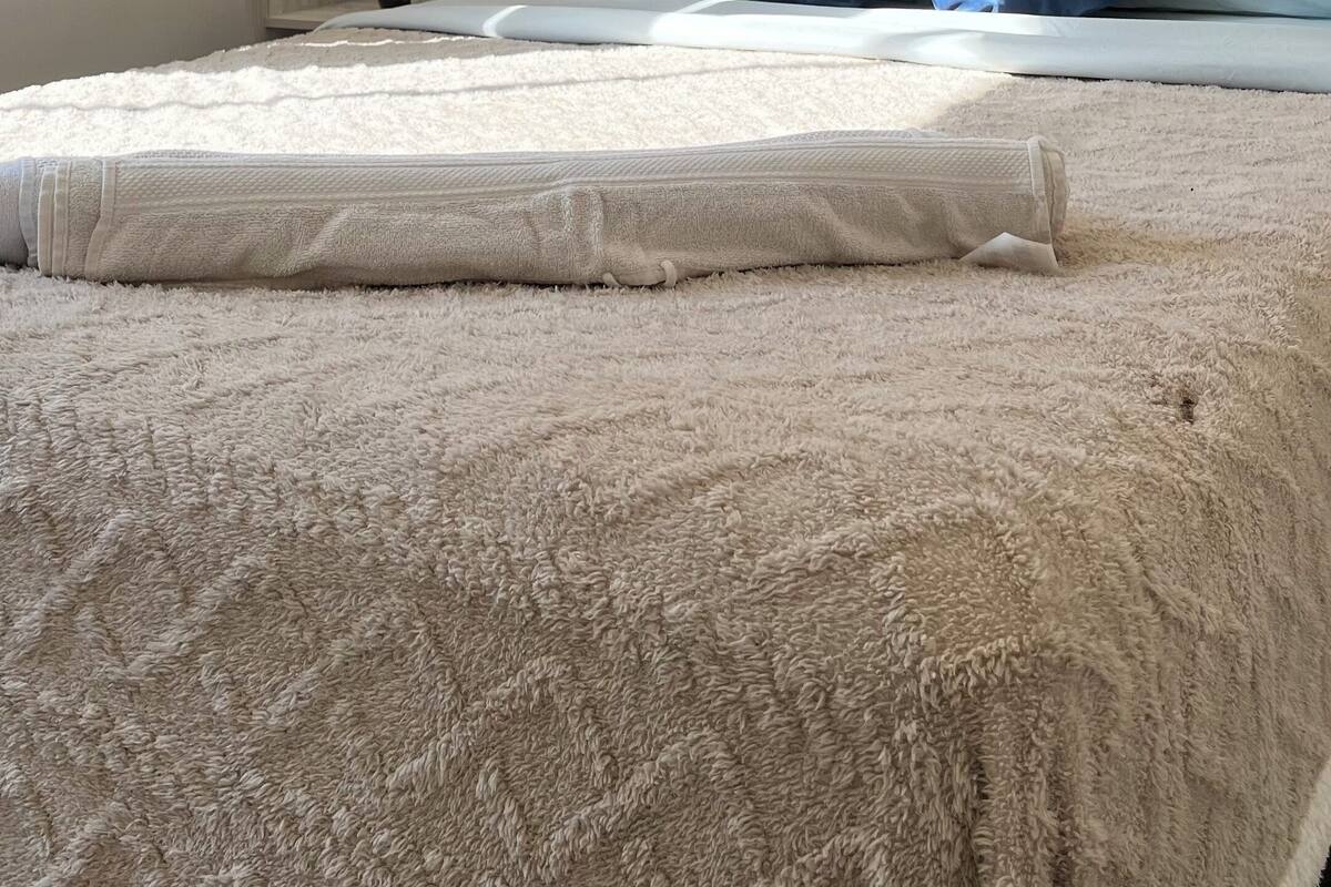 A bedroom with a bed, pillows, a nightstand, and a lamp.
