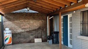 A covered outdoor area with a wooden ceiling, a large water tank, and a trash bin. - Fast Track SCL AirPort (Santiago)