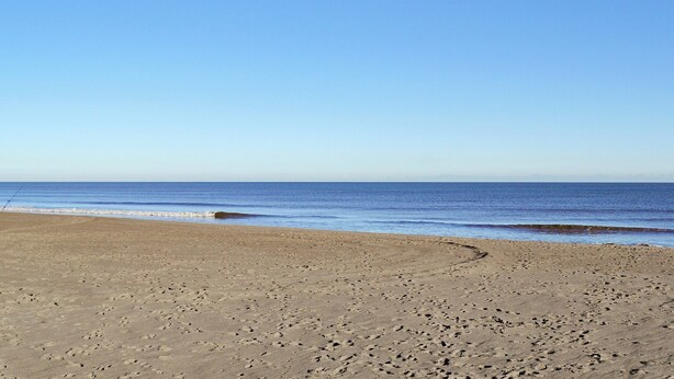 A beach with footprints leading to the water.