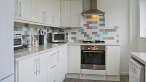 A compact kitchen with white cabinets, a microwave, a Bosch oven, and a dishwasher.