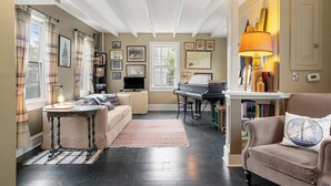 A cozy living room with a piano, a sofa, and a coffee table. - 2BR Historic Marblehead Home+Minutes to Beach (Marblehead)
