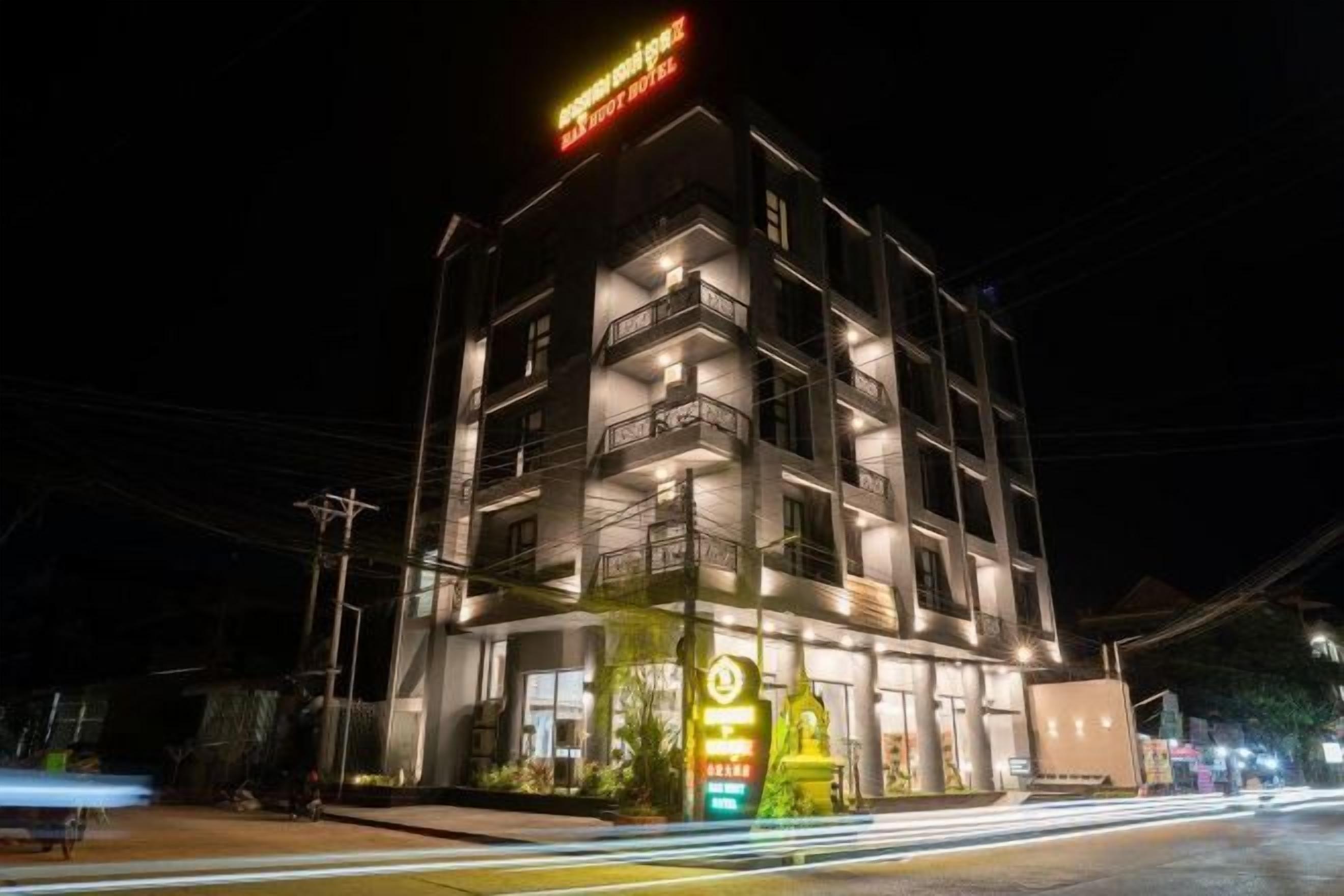 A multi-story hotel with balconies and a brightly lit sign.