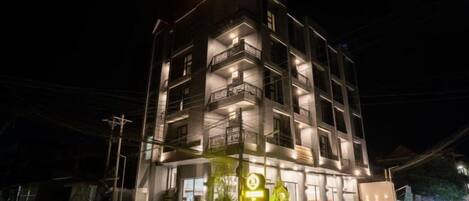 A multi-story hotel with balconies and a brightly lit sign.