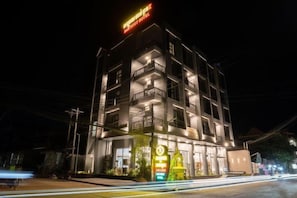 A multi-story hotel with balconies and a brightly lit sign. - Hak Heng Hotel (Krong Poi Pet)