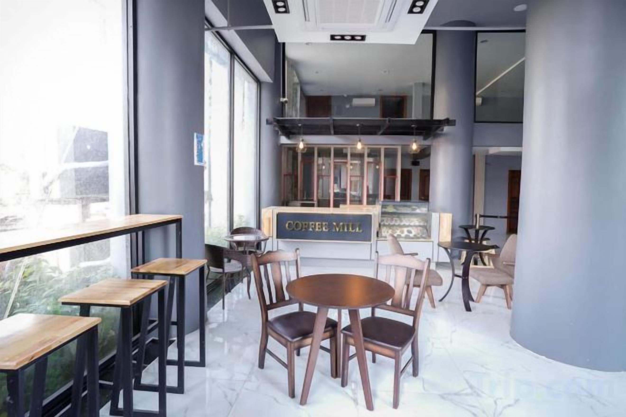 Un'area salotto interna con tavoli e sedie, una macchina da caffè e un cartello con la scritta 'COFFEE MILL'.
