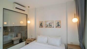 A hotel room with a bed, bedside table, lamp, and artwork on the wall.