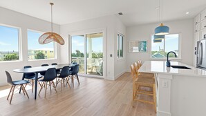 A modern kitchen with a large island, white cabinetry, and a view through the glass door.