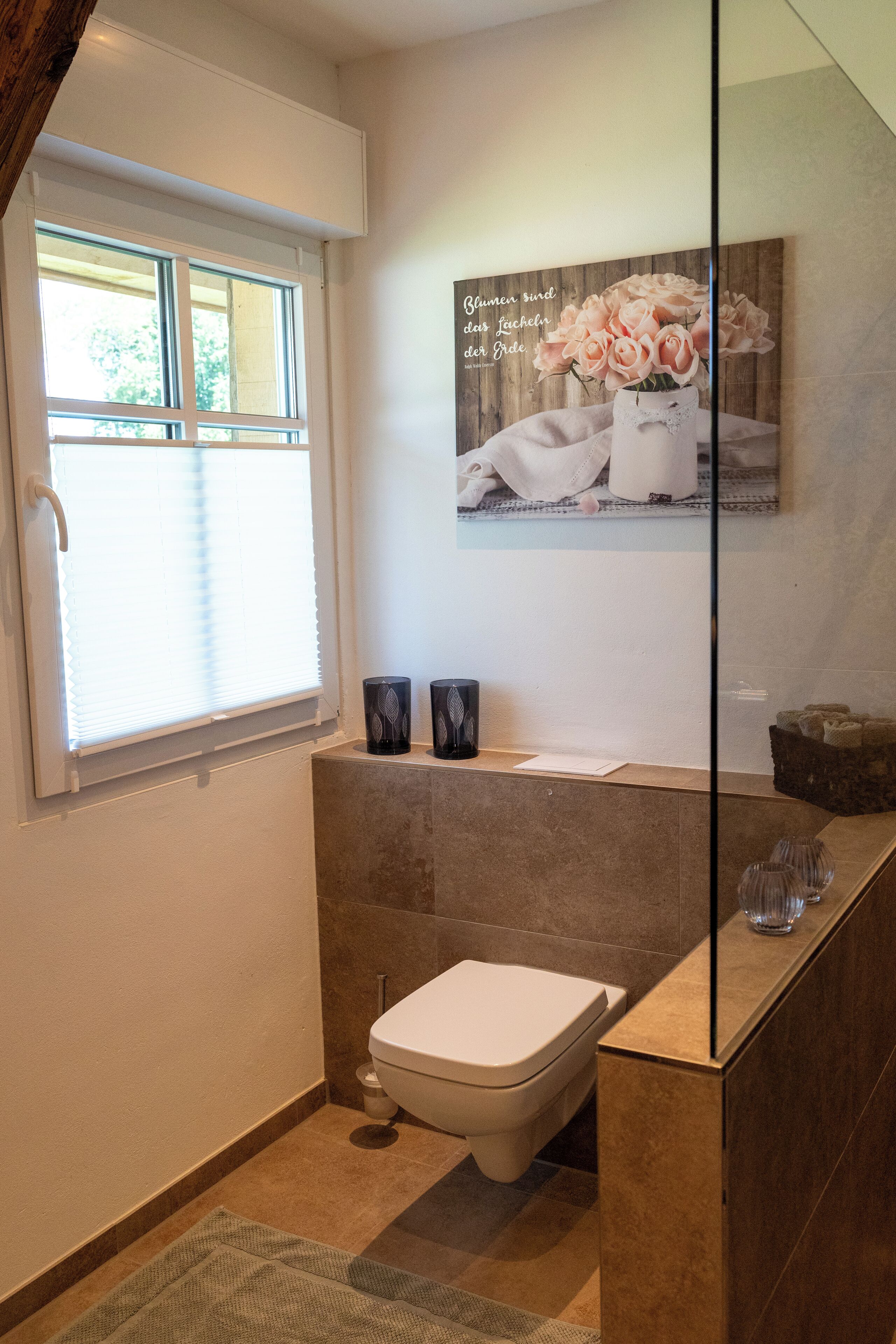 A modern bathroom with a toilet, a sink, and a window.
