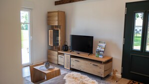 A modern bedroom with a large TV, wooden furniture, and a view of the outdoors. - Weitblick- Ruhepol in Münsterländer Parklandschaft (Dülmen)