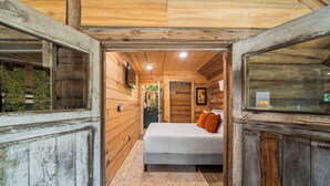 Camera da letto in una baita di legno con un letto, un comodino e una finestra.