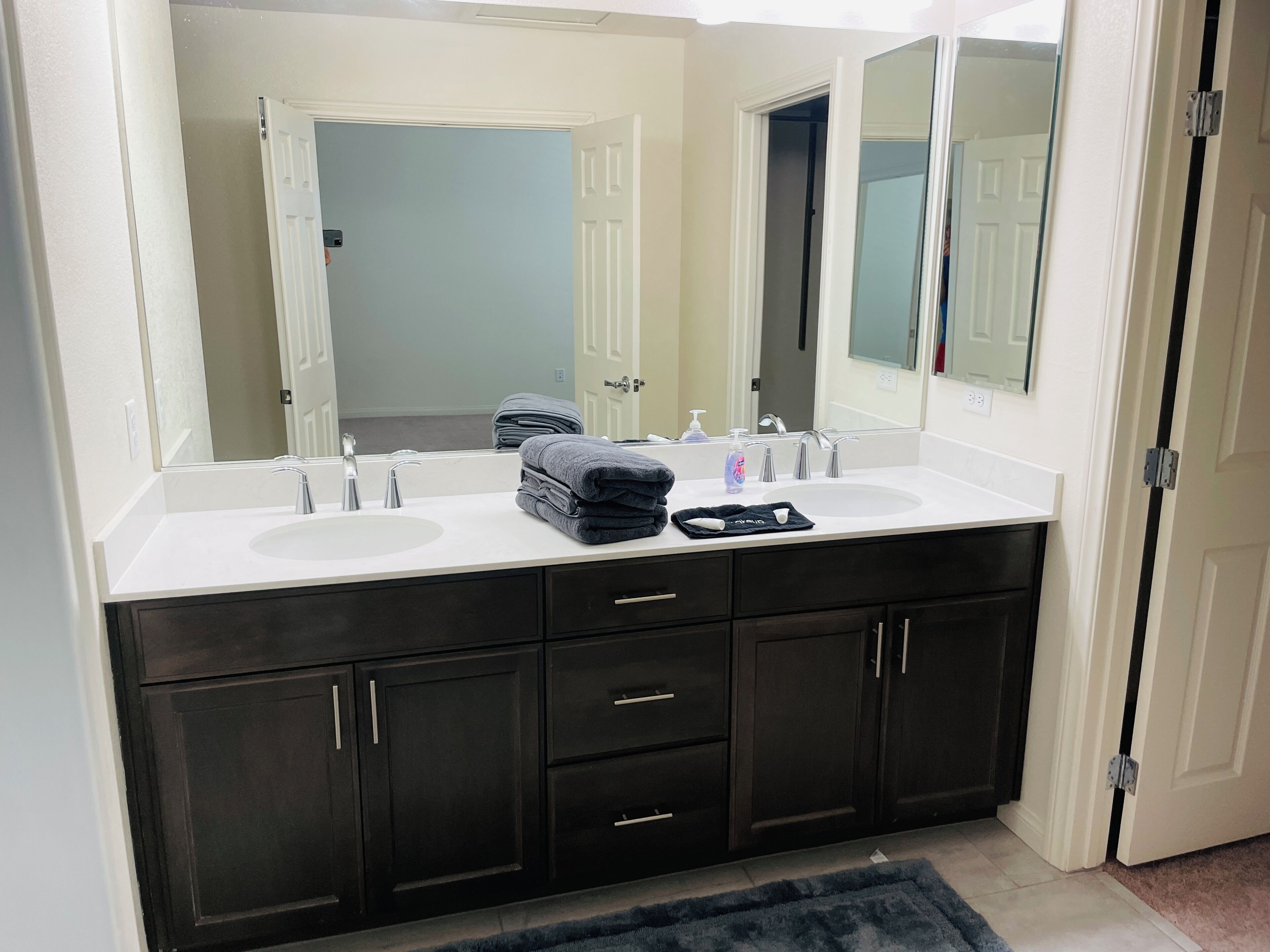 Une salle de bain avec deux lavabos, des meubles sombres et un grand miroir.
