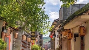 A narrow street with traditional architecture, wooden doors, and hanging lanterns. - Zijijia Inn (Shenzhen)