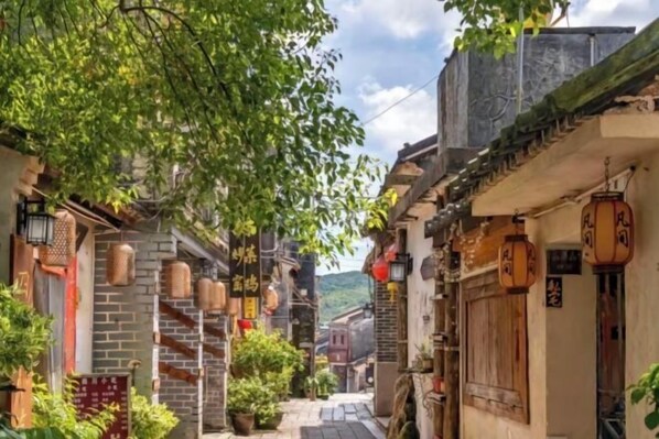 A narrow street with traditional architecture, wooden doors, and hanging lanterns. - Zijijia Inn (Shenzhen)