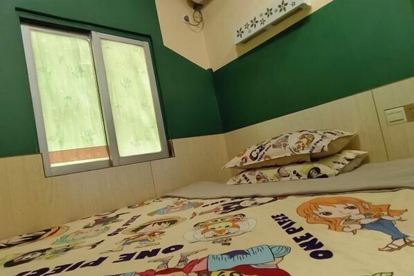 Un dormitorio con cama, almohadas, una ventana y un estante en la pared.