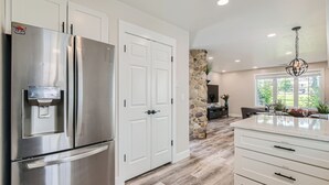 Una cucina moderna con elettrodomestici in acciaio inossidabile, mobili bianchi e una parete decorata con pietra.