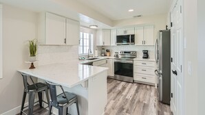 Una cucina moderna con mobili bianchi, elettrodomestici in acciaio inossidabile e un piano di lavoro in marmo.
