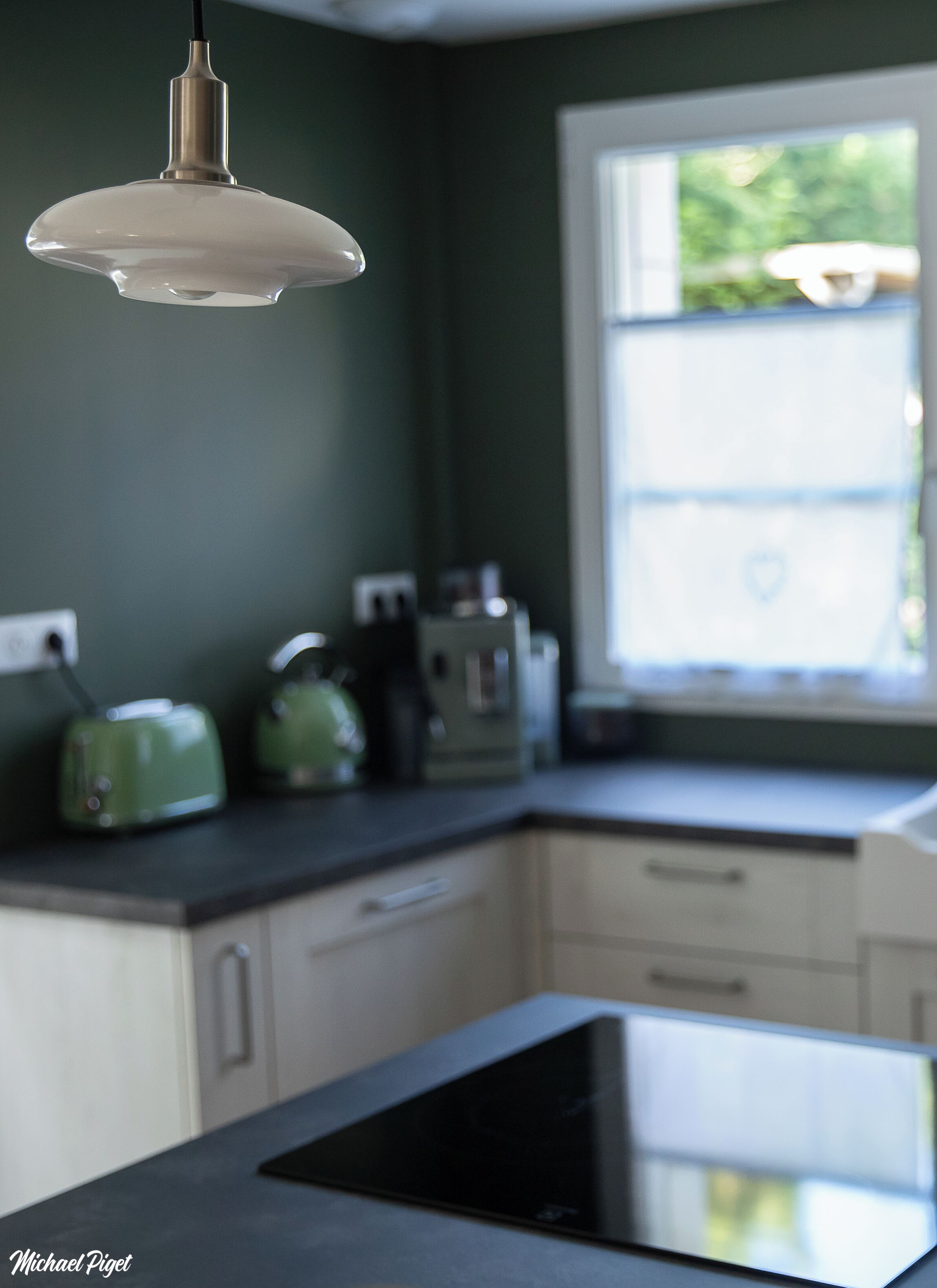 Una cocina de diseño moderno con encimera negra, estufa integrada y ventana que proporciona luz natural.