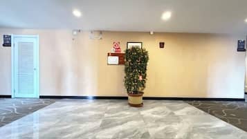 A lobby with a reception desk, a plant, a door, and a sign on the wall.