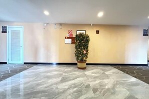 A lobby with a reception desk, a plant, a door, and a sign on the wall. - Xinyuan Hotel (Xiamen Airport Dianqian) (Xiamen)