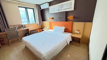 Una habitación de hotel con una cama grande, un escritorio, una silla y una mesita de noche.