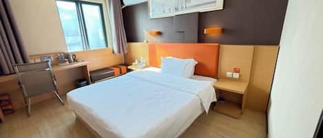 Una habitación de hotel con una cama grande, un escritorio, una silla y una mesita de noche.