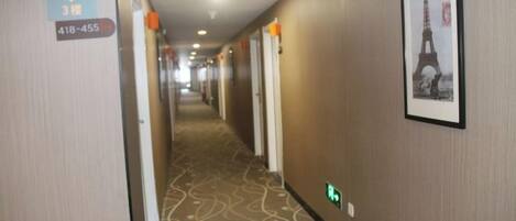 A hotel corridor with a patterned carpet, doors, and a framed picture of the Eiffel Tower.