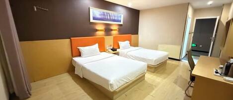 A hotel room with two beds, a desk, a chair, and a TV mounted on the wall.