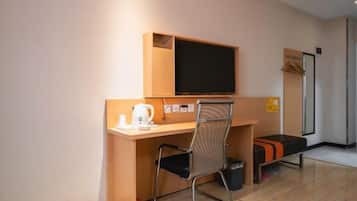 Una habitación compacta con un escritorio de madera, una silla, un televisor y un pequeño banco.