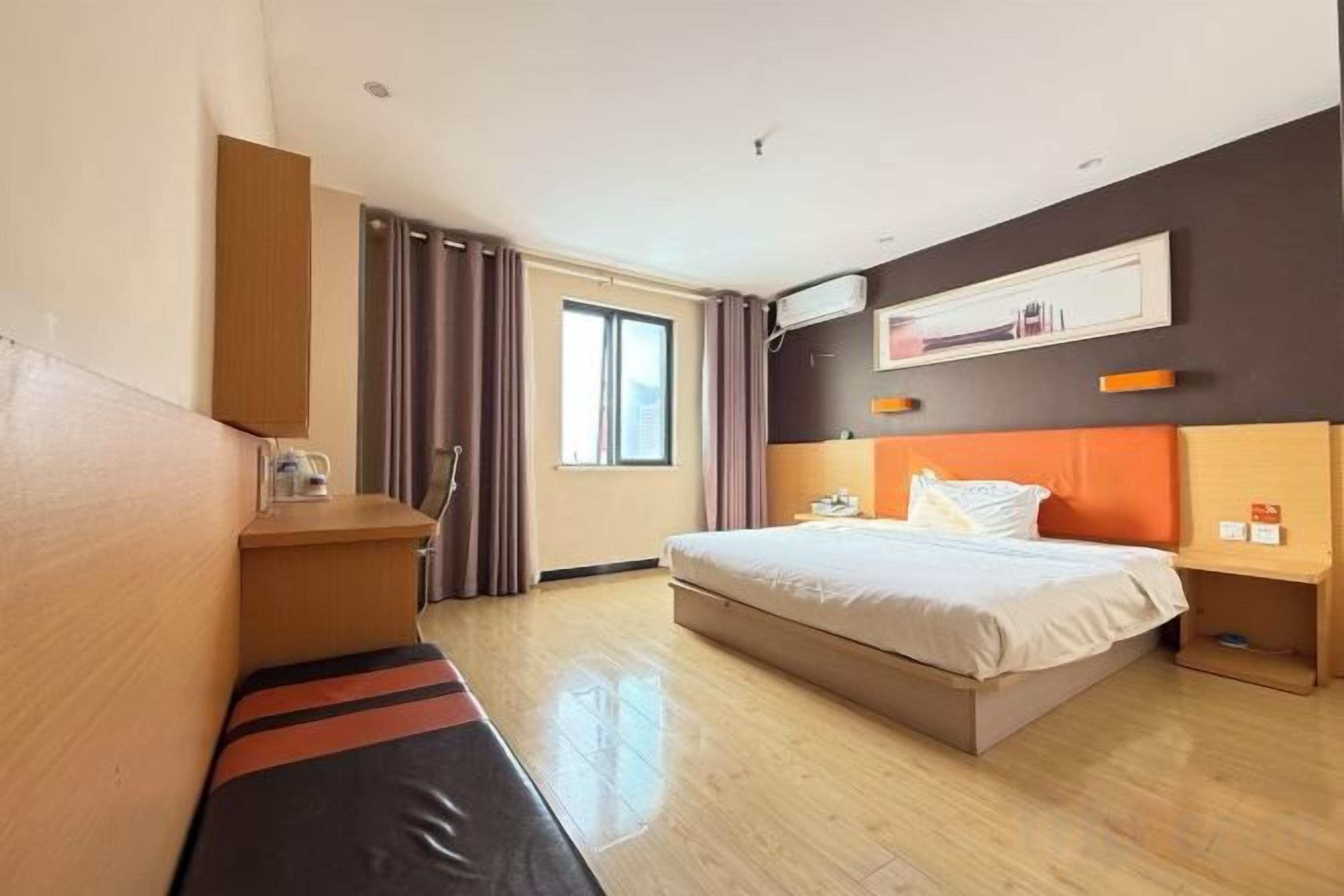 A hotel room with a bed, a desk, a chair, a window, and a curtain.
