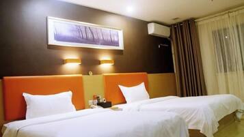 A hotel room with two beds, a large framed picture on the wall, and a window with curtains.