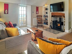 A living room with a sofa, armchairs, a fireplace, a bookshelf, and a television. - 2 bedroom accommodation in Southerness near Dumfries (Southerness near Dumfries)