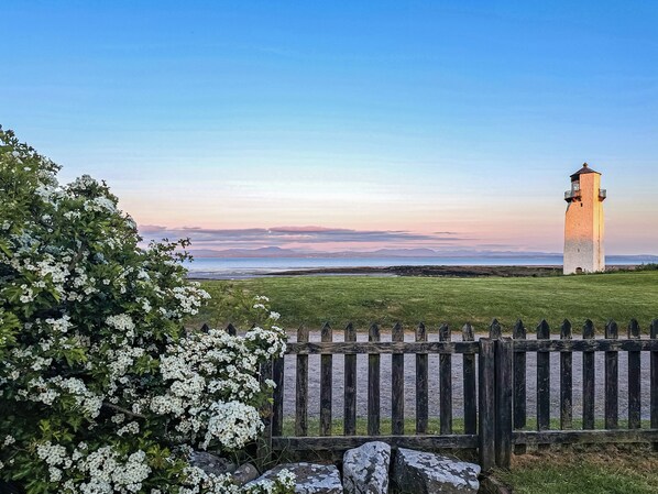 A lighthouse with a clear view of the sea and distant mountains.