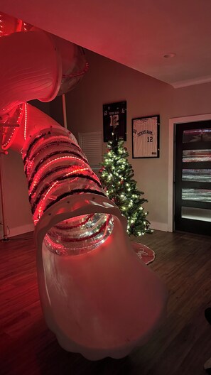 A room with a large, illuminated sculpture, a Christmas tree, and sports memorabilia on the wall. - Aggie HQ 🤠 Ring Dunk 💍• Grad 🎓• Game Day 🏈• Sleeps 12 (College Station)